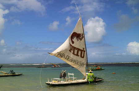 Pernambuco, Brazil July 6, 2016: An unidentified fisherman in Chicken Beach with typical sail boats in Ipojuca City near barrier reef, northeast Brazilのeditorial素材