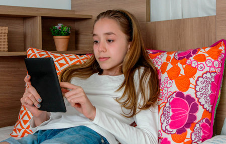 Teenager girl wearing earphone playing on tablet and listening music
