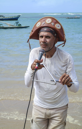 Pernambuco, Brazil July 6, 2016: An unidentified singer in Chicken Beach with typical sail boats behind in Ipojuca City near barrier reef, northeast Brazilのeditorial素材
