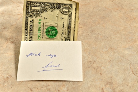 A few dollars on a table with a note to pick up food.の写真素材