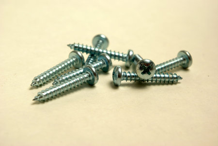 A pile of screws are on a plain white background.