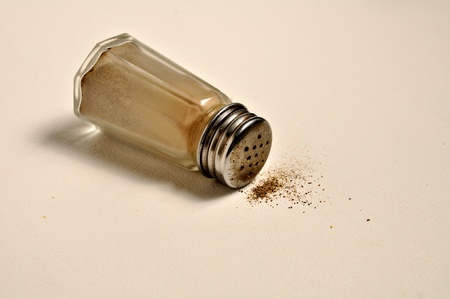 A glass pepper shaker is laying on its side.の写真素材