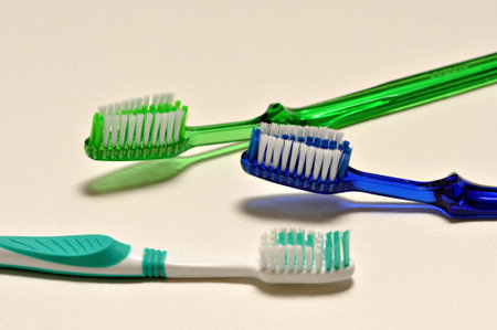 Three tooth brushes are laying on a white back ground.