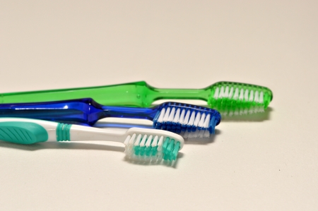 Three tooth brushes are laying on a white back ground.の写真素材
