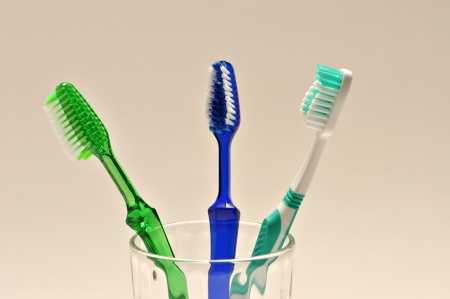 Three tooth brushes are in a glass on a white background.の写真素材
