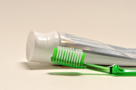 A green tooth brush lies next to a tube of tooth paste on a white background.の写真素材