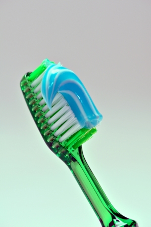 A green tooth brush with blue and white tooth paste on it の写真素材