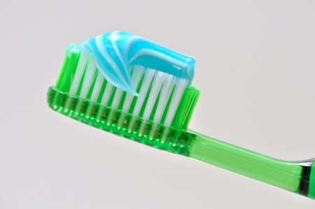 A green tooth brush with blue and white tooth paste on it の写真素材