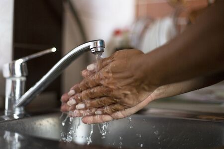 Close up of a woman washes her hands on the kitchen sinkの写真素材