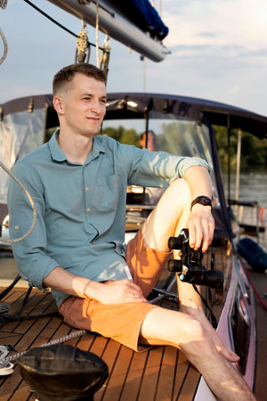 a guy in a shirt and shorts is sitting on a yacht