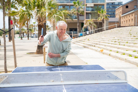 Mature man serving in table tennis matchの写真素材