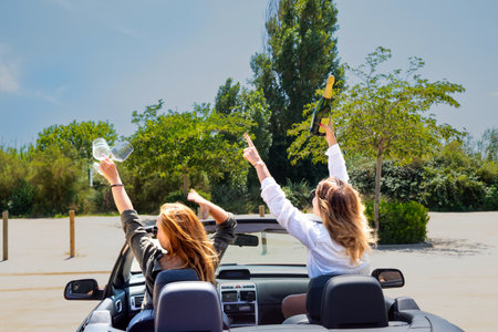 Rest and travel, two friends enjoying the moment in the car. Rear view of a convertible with friendsの写真素材