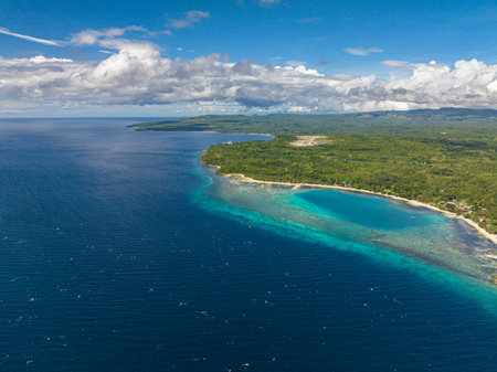 A body of land surrounded by Beautiful waves in outstanding blue ocean with a long white sandy beach. Siquijor, Philippines.の写真素材