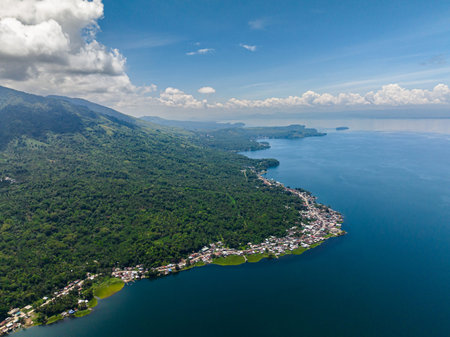 View of villages at lake coastline and mountain with jungle, forest, palm trees in Lanao del Sur....