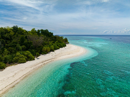 Flying over the white beach of Mantigue Island. Camiguin, Philippines. Travel destination.