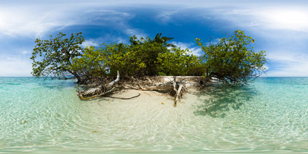 Clear ocean water over white sand beach in Mantigue Island. Blue sky and clouds. Camiguin,...
