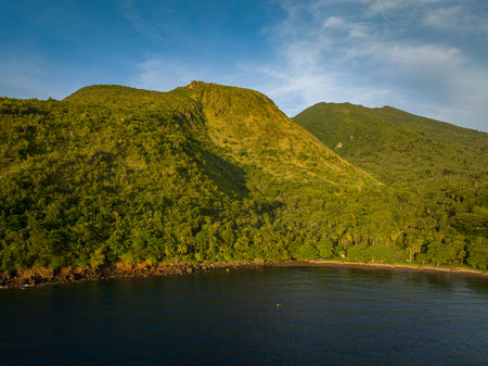 Camiguin Island with mountain cliff, valley, forest and blue sea. Blue skyand clouds. Philippines.