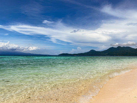 Beautiful sandy beach and ocean waves in Camiguin Island, Philippines.