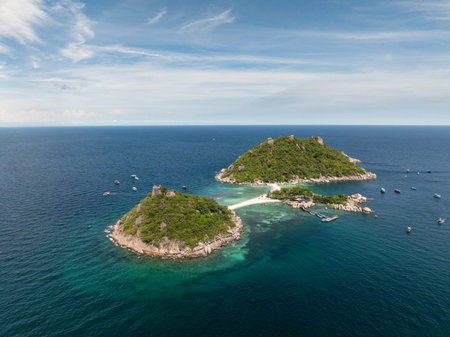 Scenic view of islands surrounded by clear water and boats anchored nearby under a bright sky. Ko...