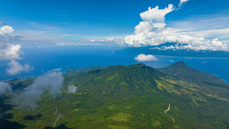 Top view of mountain with lush green forest in Camiguin Island. Blue sky and clouds. Philippines.の写真素材