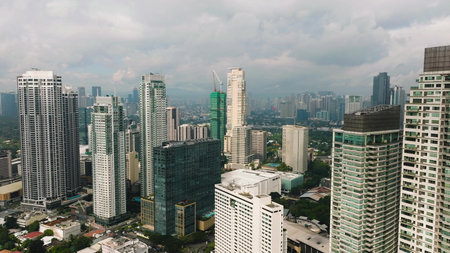 Tall buildings dominate the skyline with patches of urban greenery in a modern city. Metro Manila, Philippines.の写真素材