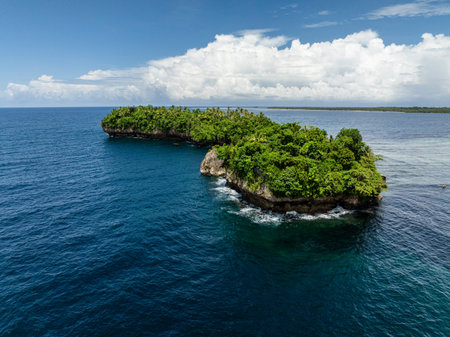 Steep rocky islets covered with green forest rising from blue ocean water. Siargao, Philippines.