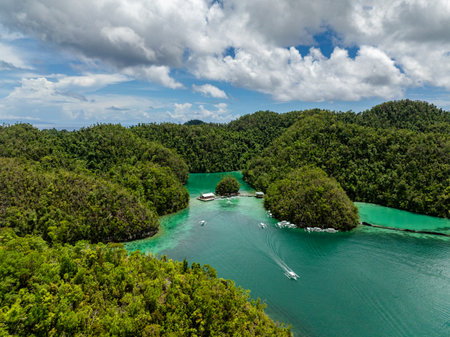 White boats sail through turquoise lagoon waters framed by forested hills. Siargao, Philippines. Sugba Blue Lagoon.の写真素材