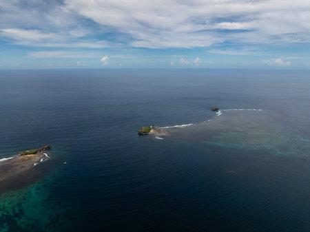 Top view of small rocky islands surrounded by shallow coral reef waters in the open ocean. Siargao, Philippines.の写真素材