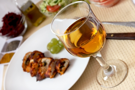 glass of wine with roast chicken, grape and salads in the backgroundの写真素材