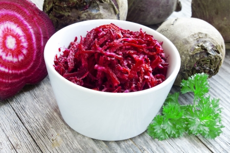 bowl of raw grated beet with parsley leaves の写真素材