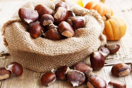 Bag with Chestnuts on Wooden Table,edible autumn fruitsの写真素材