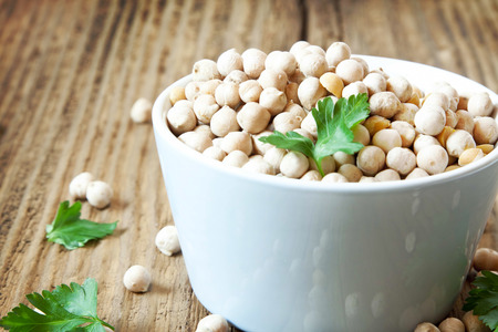 Raw Chickpeas with Parsley Leaves in a Bowl on Wooden Backgroundの写真素材