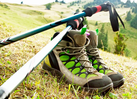 Mountain Hiking Boots and Trekking Poles on Nature Outdoor Background 