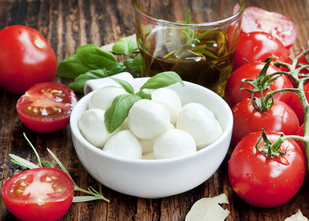Fresh Mediterranean Ingredients,Mozzarella, Basil, Olive Oil, Tomatoes and Spices for Italian Cooking Recipe on Wooden Tableの写真素材