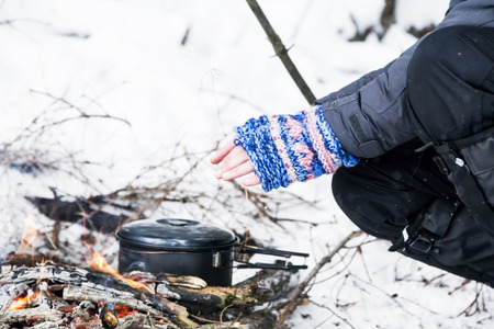 Female Hands with Handwarmers Getting Warm Near Fire Placeの写真素材