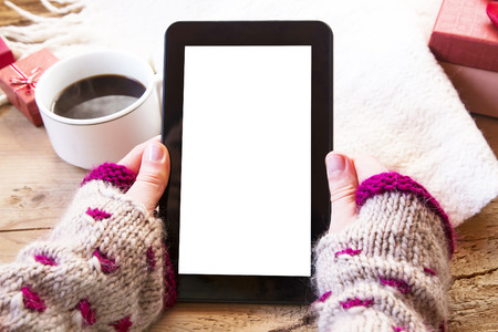 Female Hands Holding a Tablet with Coffee Cup and Christmas Gifts Nearの写真素材