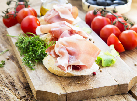 Italian Prosciutto Ham Appetizer with Spices on a Wooden Cutting Board Ready to be Servedの写真素材