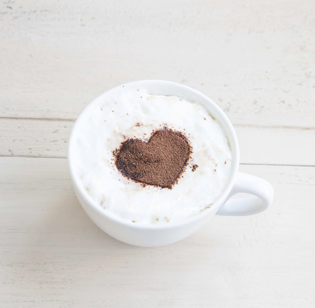 Latte Coffee Cup with Cocoa Heart Shape on Wooden Backgroundの写真素材