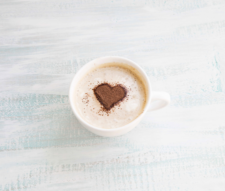 Latte Coffee Cup with Cocoa Heart Shape on Wooden Backgroundの写真素材