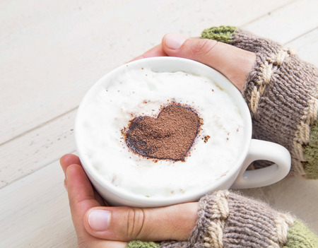 Holding Coffee Latte Cup with Cocoa Shape and Cozy Wool Hands Warmersの写真素材