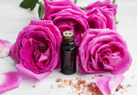 Roses essential oil in a bottle with roses and petalsの写真素材