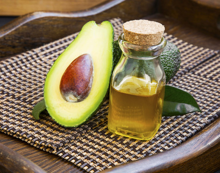 Avocado oil bottle with avocado fruit on wooden backgroundの写真素材