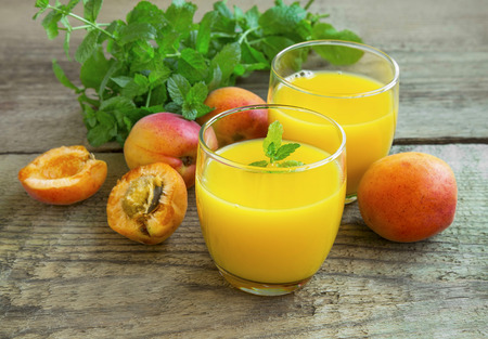 Fresh apricot juices in glasses with apricots and mint leavesの写真素材
