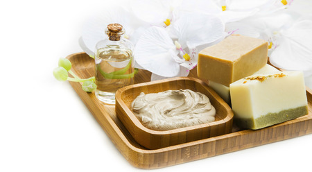 Spa still life with clay mask,natural soap,soft towel and face oil in wooden bamboo tray with orchid flowerの写真素材