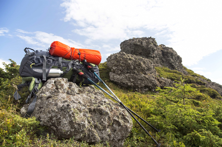 Mountain hiking equipment with backpack, isoprene, trekking sticks on a mountain rockの写真素材