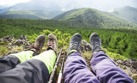 Outdoor mountain sport with hikers legs , treeking sticks and mountain boots on a mountain forest viewの写真素材
