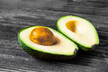 Avocado fruit cutted in two on black and white background