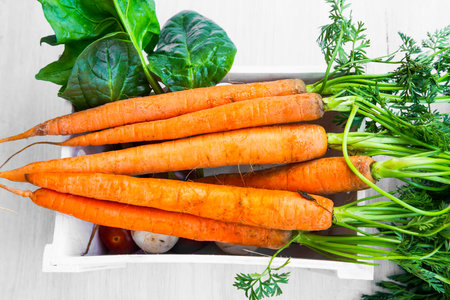 Fresh organic carrots bunch with leaves, sweet bio carrots on white crateの写真素材