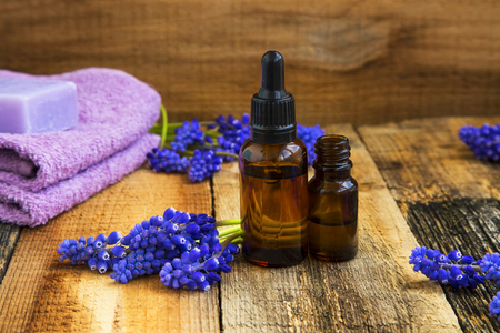 Spa set with aromatherapy oils bottles and purple flowers on wooden backgroundの写真素材