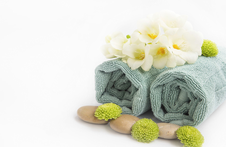 Spa still life setting with towels , massage stones and flowers, isolated on white with copy spaceの写真素材